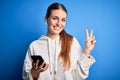 Young redhead sportswoman doing sport listening to music using earphones and smartphone smiling looking to the camera showing Royalty Free Stock Photo