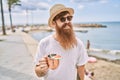 Young redhead tourist man smiling happy drinking cocktail at the beach Royalty Free Stock Photo