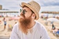 Young redhead tourist man smiling happy sitting on the bench at the beach Royalty Free Stock Photo