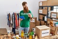 Young redhead volunteer man using touchpad holding canned food at charity center Royalty Free Stock Photo