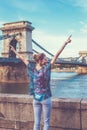 Young redhead woman arms raised and looking away at Chain Bridge, Budapest Royalty Free Stock Photo