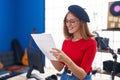 Young redhead woman artist smiling confident reading music sheet at music studio Royalty Free Stock Photo