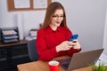 Young redhead woman business worker using laptop and smartphone at office Royalty Free Stock Photo