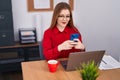 Young redhead woman business worker using laptop and smartphone at office Royalty Free Stock Photo