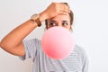 Young redhead woman chewing gum and blowing hair bubble over white isolated background stressed with hand on head, shocked with Royalty Free Stock Photo