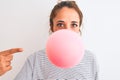 Young redhead woman chewing gum and blowing hair bubble over white isolated background very happy pointing with hand and finger Royalty Free Stock Photo