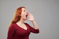 Young redhead woman creaming imitating megaphone by han