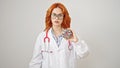 Young redhead woman doctor standing with serious expression holding doughnut over isolated white background Royalty Free Stock Photo