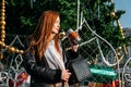 Young redhead woman drinking coffee wandering near Christmas tree in the streets on winter city. Happy young smiling Royalty Free Stock Photo