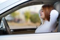 Young redhead woman driver fastened by seatbelt resting in a car smiling happily Royalty Free Stock Photo