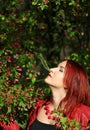 Young redhead woman enjoying cherry blossom in the sunshi