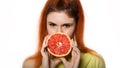 Young redhead woman with a grapefruit on a white background. concept of healthy eating