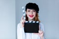 Young redhead woman in hat holding movie clapboard Royalty Free Stock Photo