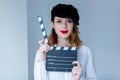 Young redhead woman in hat holding movie clapboard Royalty Free Stock Photo