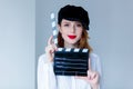 Young redhead woman in hat holding movie clapboard Royalty Free Stock Photo