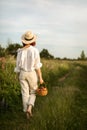 A young redhead woman holding a basket of ripe peaches and walking on the countryside road Royalty Free Stock Photo