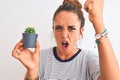 Young redhead woman holding cactus plant pot over isolated background annoyed and frustrated shouting with anger, crazy and Royalty Free Stock Photo