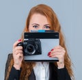 Young redhead woman holding a camera and a tablet. Royalty Free Stock Photo