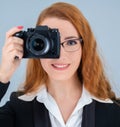 Young redhead woman holding a camera. Royalty Free Stock Photo