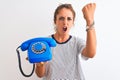 Young redhead woman holding classic retro telephone over isolated background annoyed and frustrated shouting with anger, crazy and Royalty Free Stock Photo