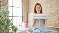 Young redhead woman holding folded towels at laundry room Royalty Free Stock Photo