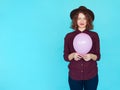 Young redhead woman holding pink balloon