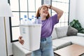 Young redhead woman holding recycling wastebasket with plastic bottles smiling confident touching hair with hand up gesture, Royalty Free Stock Photo