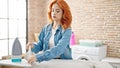 Young redhead woman ironing clothes folding shirt at laundry room Royalty Free Stock Photo