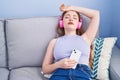 Young redhead woman listening to music relaxed on sofa at home