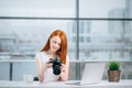 Redhead woman looking at camera while working on laptop Royalty Free Stock Photo