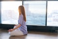 Young redhead woman meditating practicing breathing yoga exercise, sitting on floor near window in lotus position. Royalty Free Stock Photo