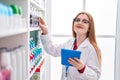 Young redhead woman pharmacist using touchpad working at pharmacy