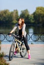 Young redhead woman riding a bike on embankment. Active people outdoors. Sport lifestyle. Royalty Free Stock Photo