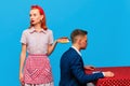 Young redhead woman serving breakfast with fried eggs and sausages to man against blue studio background. Food pop art Royalty Free Stock Photo