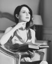 Young redhead woman sitting in chair reading book. Royalty Free Stock Photo