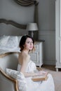 Young redhead woman sitting in chair reading book. Royalty Free Stock Photo