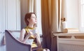 Young redhead woman sitting in chair reading book. Royalty Free Stock Photo