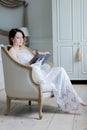 Young redhead woman sitting in chair reading book. Royalty Free Stock Photo