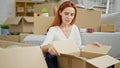 Young redhead woman sitting on floor unpacking at new home Royalty Free Stock Photo