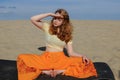 Young redhead woman sitting in purna titli yoga pose on the beach