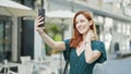 Young redhead woman smiling confident making selfie by the smartphone at coffee shop terrace Royalty Free Stock Photo