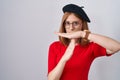 Young redhead woman standing wearing glasses and beret doing time out gesture with hands, frustrated and serious face