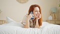 Young redhead woman talking on smartphone lying on bed at bedroom Royalty Free Stock Photo