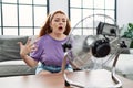 Young redhead woman using electric ventilator at home