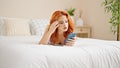 Young redhead woman using smartphone lying on bed at bedroom Royalty Free Stock Photo