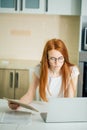 Redhead using the tablet pc and laptop in kitchen Royalty Free Stock Photo