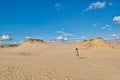 Young redhead woman walking under sun along endless sandy dunes Royalty Free Stock Photo