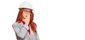 Young redhead woman wearing architect hardhat bored yawning tired covering mouth with hand Royalty Free Stock Photo
