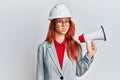 Young redhead woman wearing architect hardhat and megaphone clueless and confused expression Royalty Free Stock Photo
