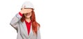 Young redhead woman wearing architect hardhat smiling and laughing with hand on face covering eyes for surprise Royalty Free Stock Photo